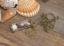 Hänge med snäckor och sjöstjärna i glasbehållare, dekorerad med bronspläterad berlock med texten Dreaming of the sea. Levereras