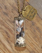 Hänge med snäckor och sjöstjärna i glasbehållare, dekorerad med bronspläterad berlock med texten Dreaming of the sea. Levereras