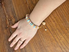 Handgjort sommararmband med färgglada snäckbitar, emaljerad blomcharm och vit sötvattenspärla. Justerbart med 3 cm förlängningsk