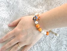 Unikt handgjort armband med vita sötvattenspärlor, orange porslinspärlor och tropisk fisk-berlock. Tillverkat med 18K guldpläter