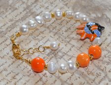 Unikt handgjort armband med vita sötvattenspärlor, orange porslinspärlor och tropisk fisk-berlock. Tillverkat med 18K guldpläter