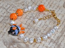 Unikt handgjort armband med vita sötvattenspärlor, orange porslinspärlor och tropisk fisk-berlock. Tillverkat med 18K guldpläter