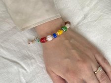 Handgjort färgglatt armband med millefiori-glaspärlor i regnbågens färger och gyllene prästkrage-detaljer. Armbandet har justerb