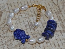 Handgjort armband med djupblå lapis lazuli, gyllene pyrit, vita sötvattenspärlor och en porslinsfisk. Justerbart med 3 cm förlän