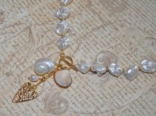 Elegant halsband med sötvattenssnäckor, vit pärla och guldförgyllda detaljer – kustinspirerat statement-smycke med toggle-lås i 