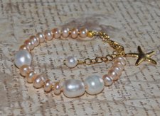 Handgjort armband med vita och persikofärgade sötvattenspärlor, dekorerat med 18K guldförgyllt sjöstjärnehänge. Perfekt för merm