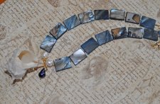 Statement-halsband med stora mörkblå pärlemorpärlor, vita sötvattenspärlor och gyllene glaspärlor, med vitt snäckskal och svart 