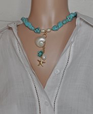 Handgjort halsband med turkosa howlit-nuggets, vita sötvattenspärlor och gyllene seed beads. Hänge med turbosnäcka, howlit-sköld