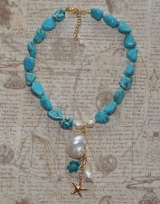 Handgjort halsband med turkosa howlit-nuggets, vita sötvattenspärlor och gyllene seed beads. Hänge med turbosnäcka, howlit-sköld