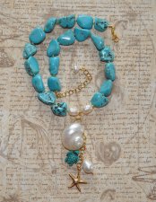 Handgjort halsband med turkosa howlit-nuggets, vita sötvattenspärlor och gyllene seed beads. Hänge med turbosnäcka, howlit-sköld