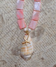 Handgjort halsband med korallrosa pärlemorpärlor, sötvattenspärlor och gyllene seed beads. Center med Alphabet Cone-snäcka och 1