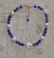 Choker-halsband med vita sötvattensskalpärlor, koboltblå evil eye-porcelänpärlor och frostade blå glaspärlor. 18K guldpläterade 