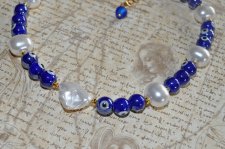 Choker-halsband med vita sötvattensskalpärlor, koboltblå evil eye-porcelänpärlor och frostade blå glaspärlor. 18K guldpläterade 