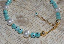 Chokerhalsband med vita snäckskalpärlor, turkosa Evil Eye-detaljer och snäcknugget i mitten. Justerbart halsband i rostfritt stå