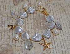 Handgjort armband med vita elektropläterade sötvattensskal-nuggets, snäckor, sötvattenspärlor och 18K guldpläterade delfin- och 