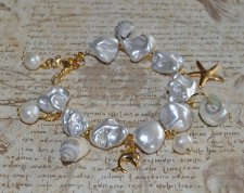 Handgjort armband med vita elektropläterade sötvattensskal-nuggets, snäckor, sötvattenspärlor och 18K guldpläterade delfin- och 