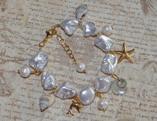 Handgjort armband med vita elektropläterade sötvattensskal-nuggets, snäckor, sötvattenspärlor och 18K guldpläterade delfin- och 