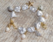 Handgjort armband med vita elektropläterade sötvattensskal-nuggets, snäckor, sötvattenspärlor och 18K guldpläterade delfin- och 