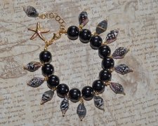 Handgjort Mermaidcore-armband med svart, vitt och brunt snäckskal, svarta porslinspärlor och guldpläterad sjöstjärna. Justerbart