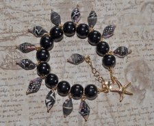 Handgjort Mermaidcore-armband med svart, vitt och brunt snäckskal, svarta porslinspärlor och guldpläterad sjöstjärna. Justerbart