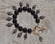 Handgjort Mermaidcore-armband med svart, vitt och brunt snäckskal, svarta porslinspärlor och guldpläterad sjöstjärna. Justerbart