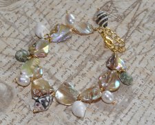 Sommararmband med Alabaster Beige AB snäckpärlor, varma guldfärgade glaspärlor, vita sötvattenspärlor och naturliga snäckor. Jus