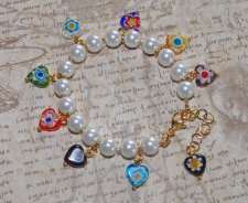 Färgstarkt Y2K-armband med vita fauxpärlor, guldfärgade glaspärlor och lekfulla Millefiori-hjärtpärlor i glas. Justerbart armban