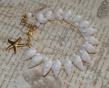 Handgjort armband med vita spiralsnäckor, pärlemorpärlor och ett guldfärgat sjöstjärnehänge. Havsinspirerat smycke i mermaidcore