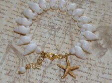 Handgjort armband med vita spiralsnäckor, pärlemorpärlor och ett guldfärgat sjöstjärnehänge. Havsinspirerat smycke i mermaidcore