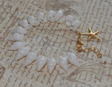 Handgjort armband med vita spiralsnäckor, pärlemorpärlor och ett guldfärgat sjöstjärnehänge. Havsinspirerat smycke i mermaidcore
