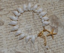 Handgjort armband med vita spiralsnäckor, pärlemorpärlor och ett guldfärgat sjöstjärnehänge. Havsinspirerat smycke i mermaidcore