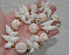 Handgjord naturinspirerad choker med äkta vita spiralformade snäckor, guldfärgade träpärlor och iögonfallande trumpetsnäckor. Ju