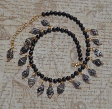 Gotisk sjöjungfru-choker med svarta ebenholtspärlor och mörka spiralformade snäckor. Justerbar längd med 18K guldförgyllda detal
