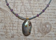 Handgjort mermaidcore choker-halsband med iriserande seed beads och facetterade ametistpärlor, prytt med en naturlig paua-snäcka