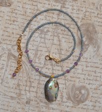 Handgjort mermaidcore choker-halsband med iriserande seed beads och facetterade ametistpärlor, prytt med en naturlig paua-snäcka