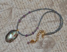 Handgjort mermaidcore choker-halsband med iriserande seed beads och facetterade ametistpärlor, prytt med en naturlig paua-snäcka