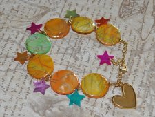 Färgglatt Y2K-armband med pärlemorsmynt i gul, orange och grön, samt flerfärgade pärlemorsstjärnor. Dekorerat med 18K guldpläter