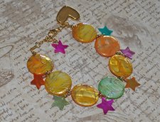 Färgglatt Y2K-armband med pärlemorsmynt i gul, orange och grön, samt flerfärgade pärlemorsstjärnor. Dekorerat med 18K guldpläter