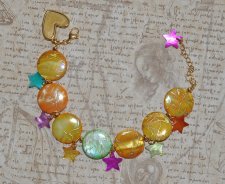 Färgglatt Y2K-armband med pärlemorsmynt i gul, orange och grön, samt flerfärgade pärlemorsstjärnor. Dekorerat med 18K guldpläter