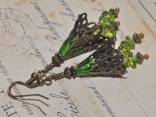 Handgjorda örhängen i Fairycore-stil med bronsfärgade filigranblommor och polerade peridotpärlor som glimmar i grönt. De svängan