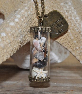 Hänge med snäckor och sjöstjärna i glasbehållare, dekorerad med bronspläterad berlock med texten Dreaming of the sea. Levereras