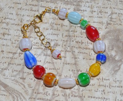 Handgjort färgglatt armband med millefiori-glaspärlor i regnbågens färger och gyllene prästkrage-detaljer. Armbandet har justerb