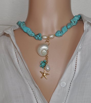 Handgjort halsband med turkosa howlit-nuggets, vita sötvattenspärlor och gyllene seed beads. Hänge med turbosnäcka, howlit-sköld