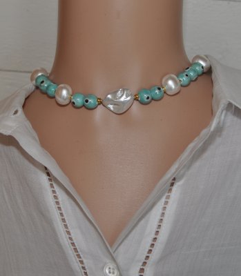 Chokerhalsband med vita snäckskalpärlor, turkosa Evil Eye-detaljer och snäcknugget i mitten. Justerbart halsband i rostfritt stå