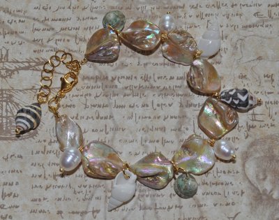 Sommararmband med Alabaster Beige AB snäckpärlor, varma guldfärgade glaspärlor, vita sötvattenspärlor och naturliga snäckor. Jus