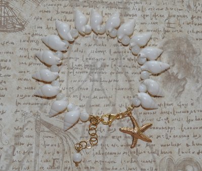 Handgjort armband med vita spiralsnäckor, pärlemorpärlor och ett guldfärgat sjöstjärnehänge. Havsinspirerat smycke i mermaidcore