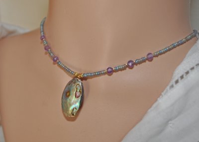 Handgjort mermaidcore choker-halsband med iriserande seed beads och facetterade ametistpärlor, prytt med en naturlig paua-snäcka
