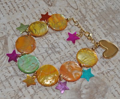 Färgglatt Y2K-armband med pärlemorsmynt i gul, orange och grön, samt flerfärgade pärlemorsstjärnor. Dekorerat med 18K guldpläter